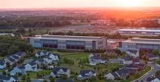 Aerial view of a neighborhood at sunset with a large data center building beyond the rooftops